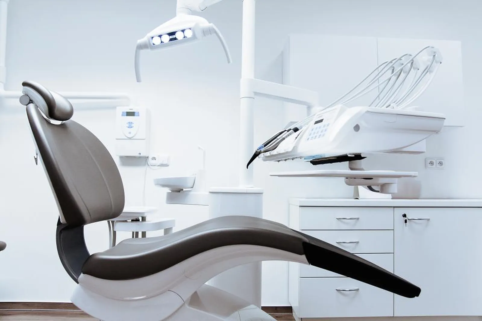 A bright dental treatment room with the chair, light and instrument tray.